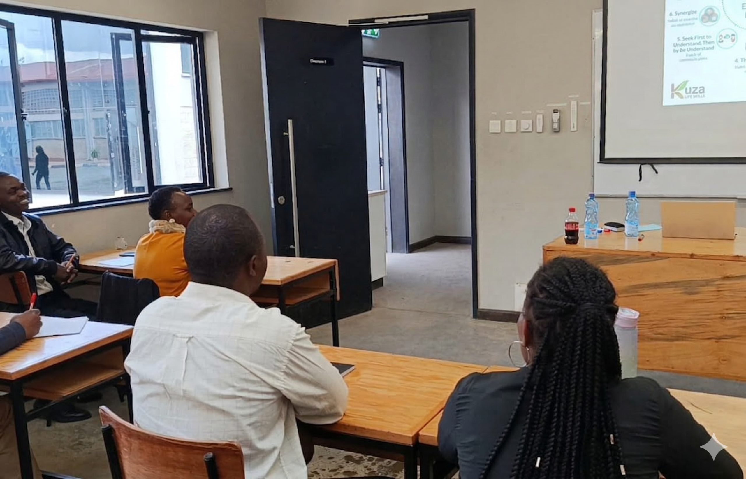 A diverse group of focused young Kenyan professionals attending a soft skills workshop